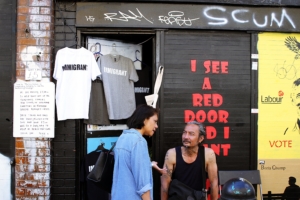 Expats in front of a shop, "Immigrant" T-shirt for sale