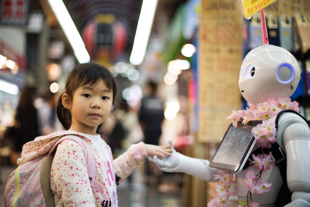 Asian little girl holding hand with a robot her size